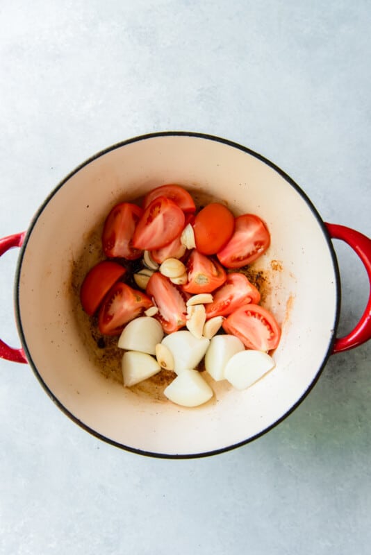 onion quarters and tomato quarters in a Dutch oven