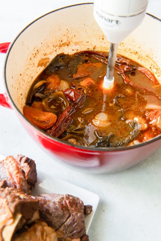 immersion blender in a Dutch oven with tomatoes, peppers, and broth