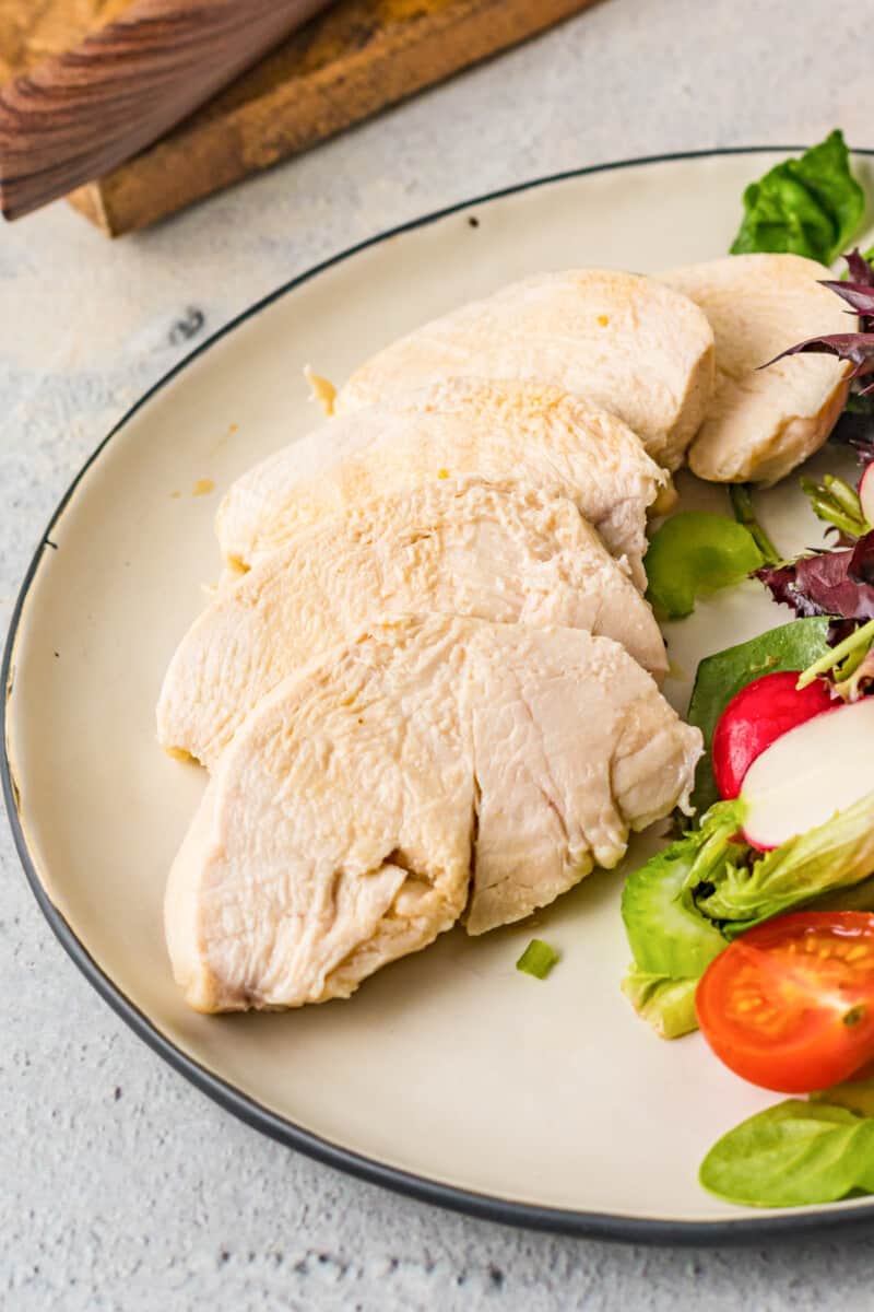 sliced poached chicken breast on a white plate