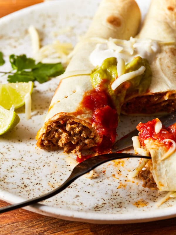 beef taquitos on a white plate with a fork.