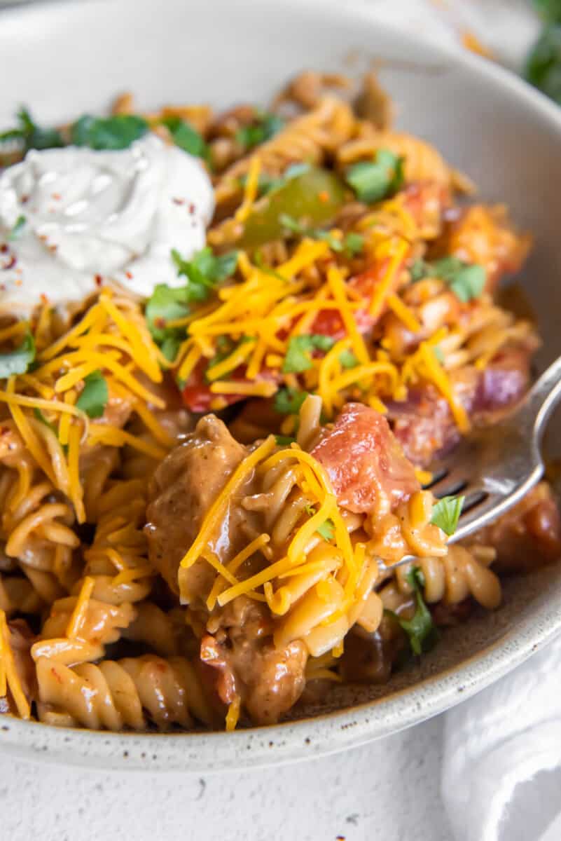 chicken fajita pasta in a white bowl with a fork