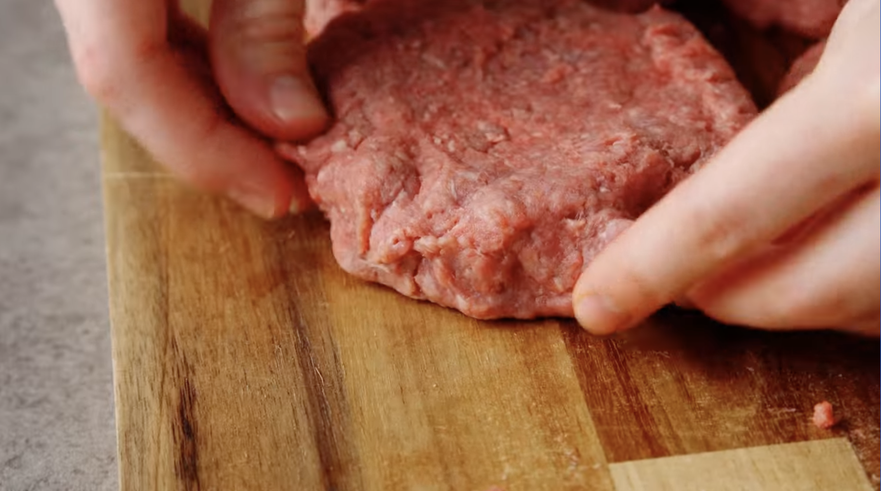 sealing a burger patty filled with cheese.