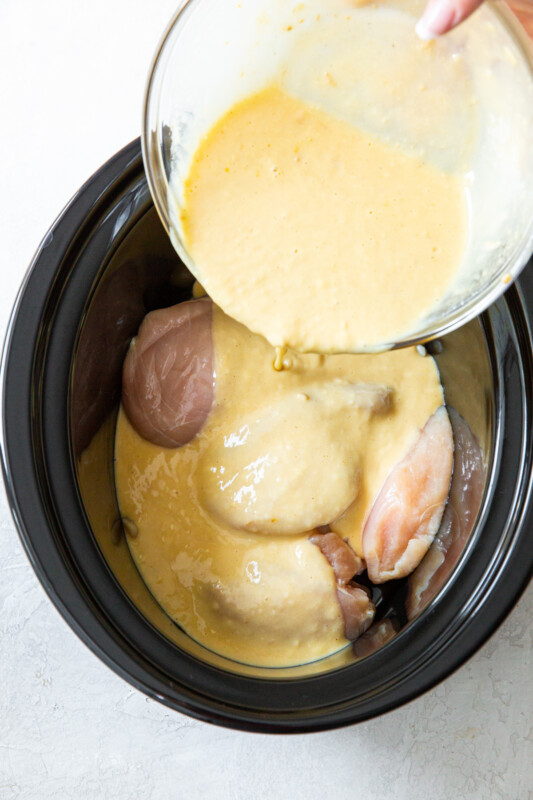 gravy poured over chicken in a crockpot.