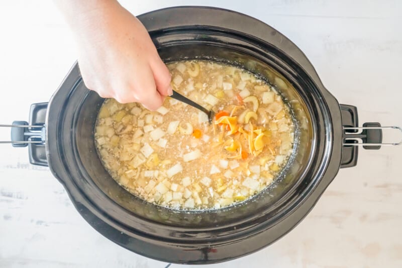 noodles stirred into crockpot chicken noodle soup in a crockpot.