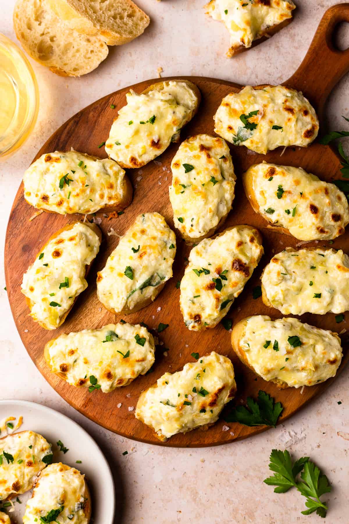 bruschetta topped with artichoke dip on a wooden platter.