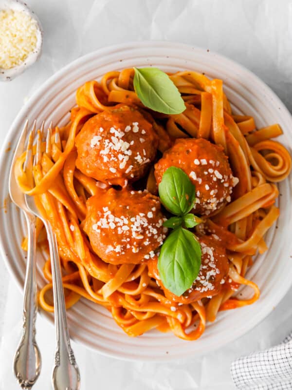 overhead view of chicken parmesan meatballs in a white bowl with a fork and spoon.