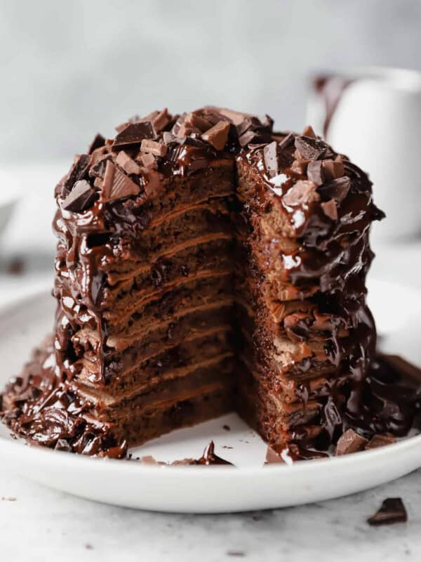 A delectable stack of chocolate pancakes, warm and fluffy, is delicately placed on a pristine plate.