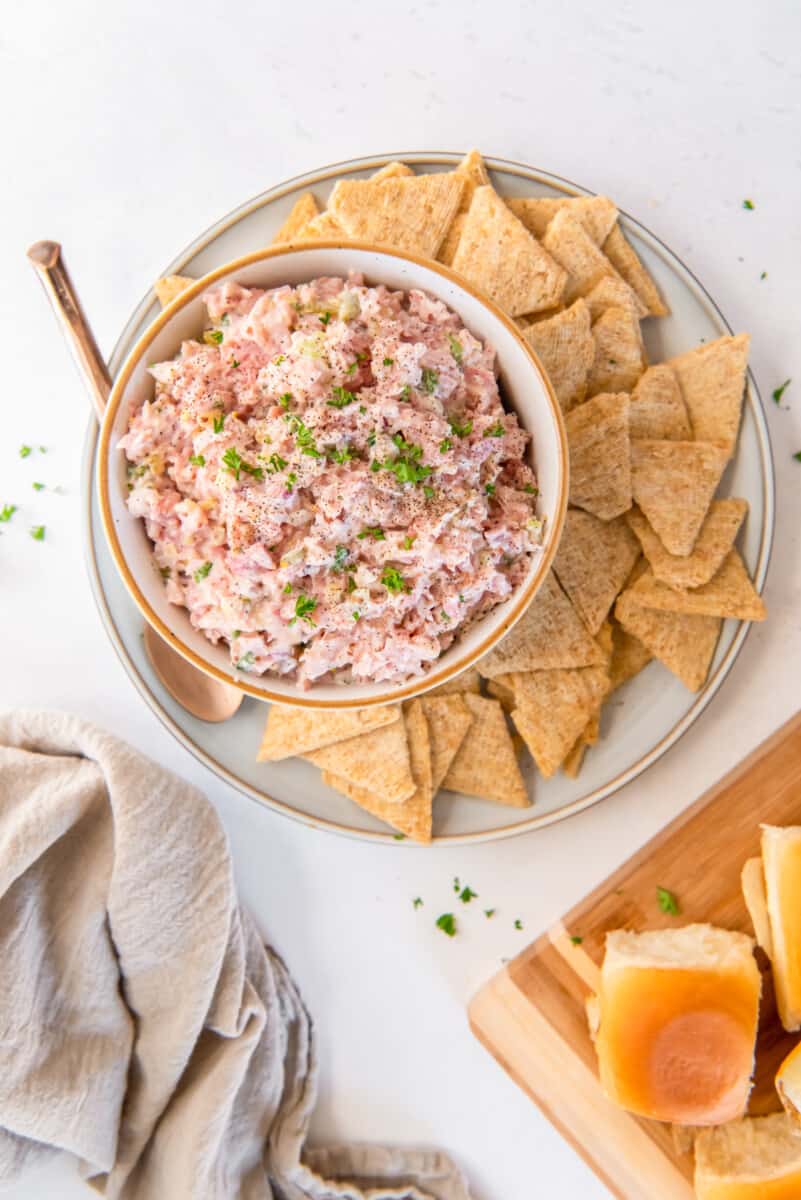 ham salad in a white bowl on a white plate with triscuits.