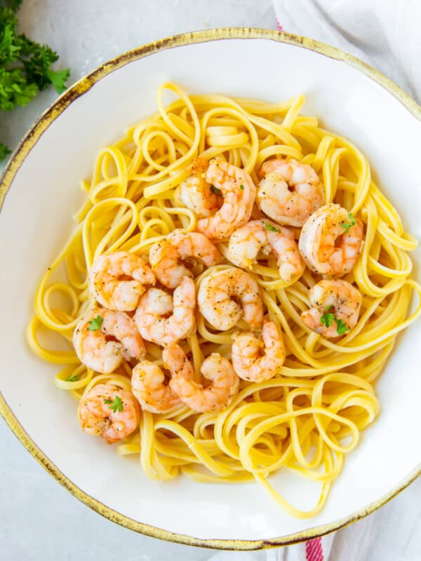 air fryer garlic shrimp over spaghetti on a white plate.