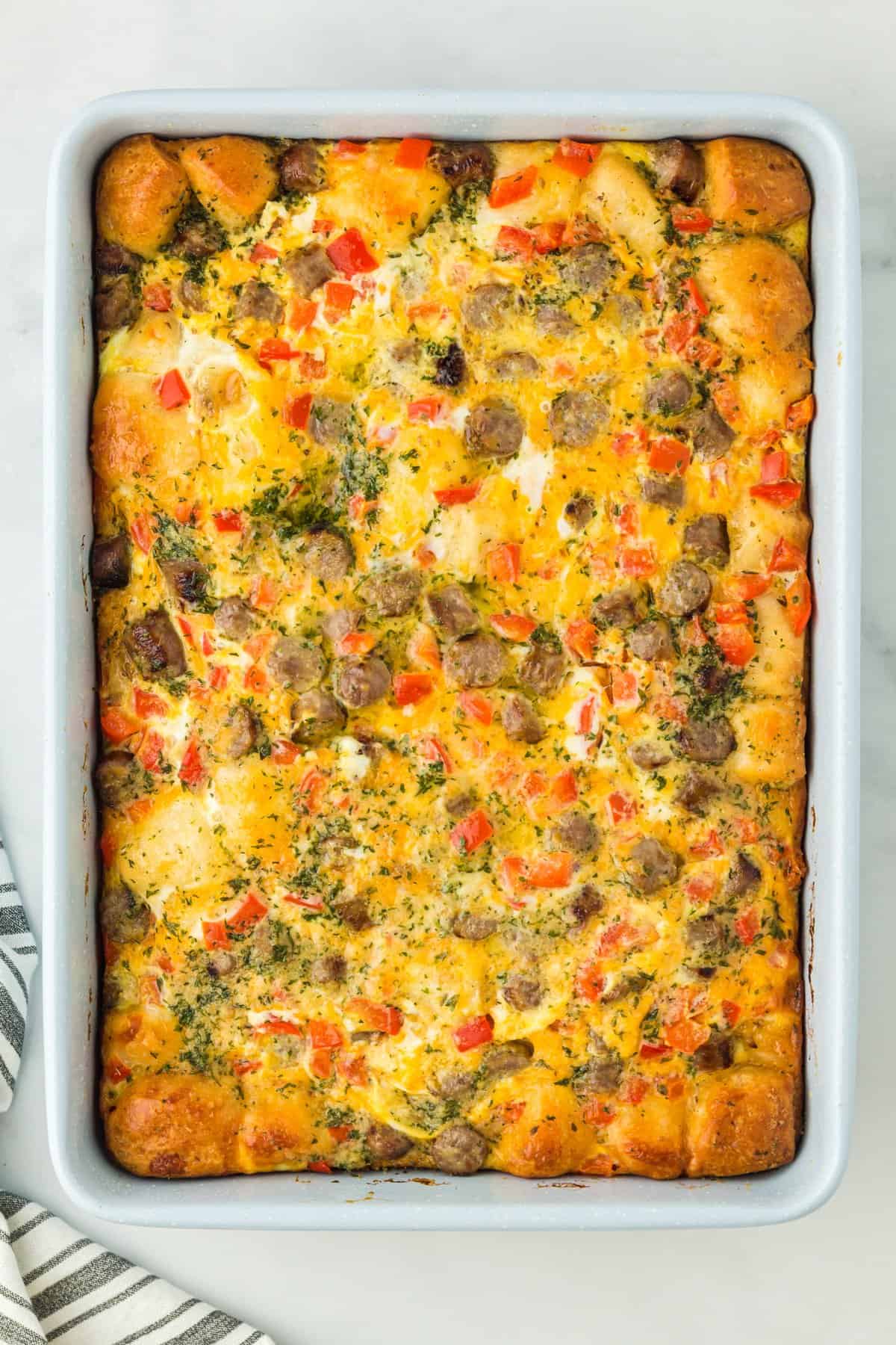 casserole with eggs, sausage, biscuits, and bell peppers in a baking pan.