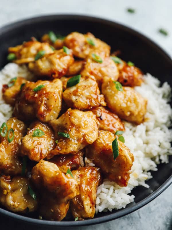 honey chicken over white rice in a black bowl.