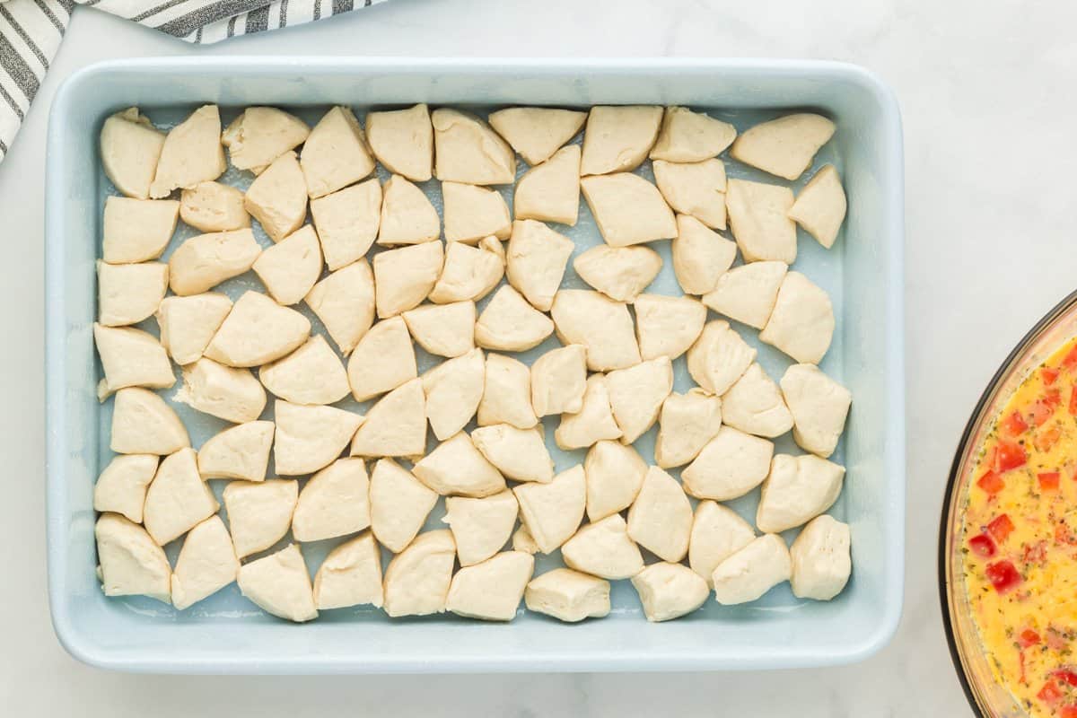 Pieces of biscuit dough arranged in a baking dish.