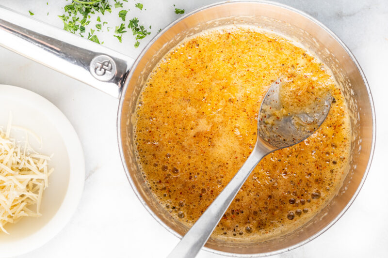 garlic parmesan butter in a saucepan with a spoon.