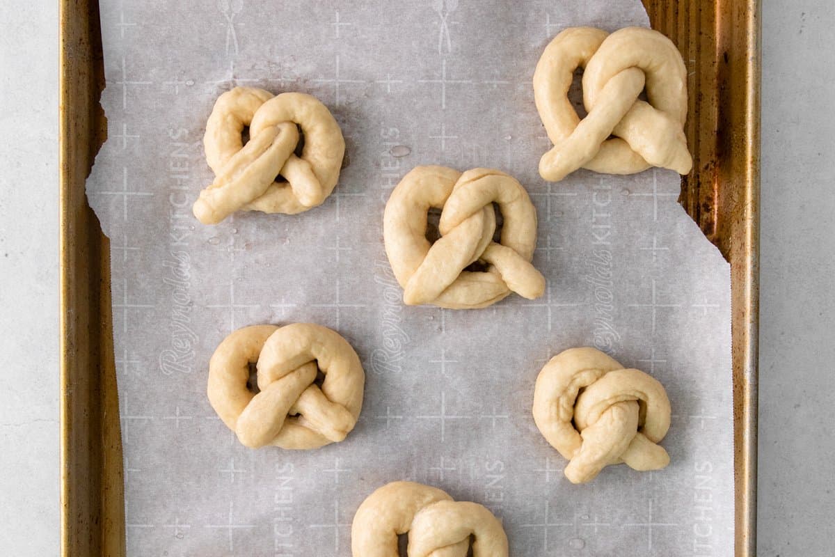 shaped garlic parmesan soft pretzels on a baking sheet.