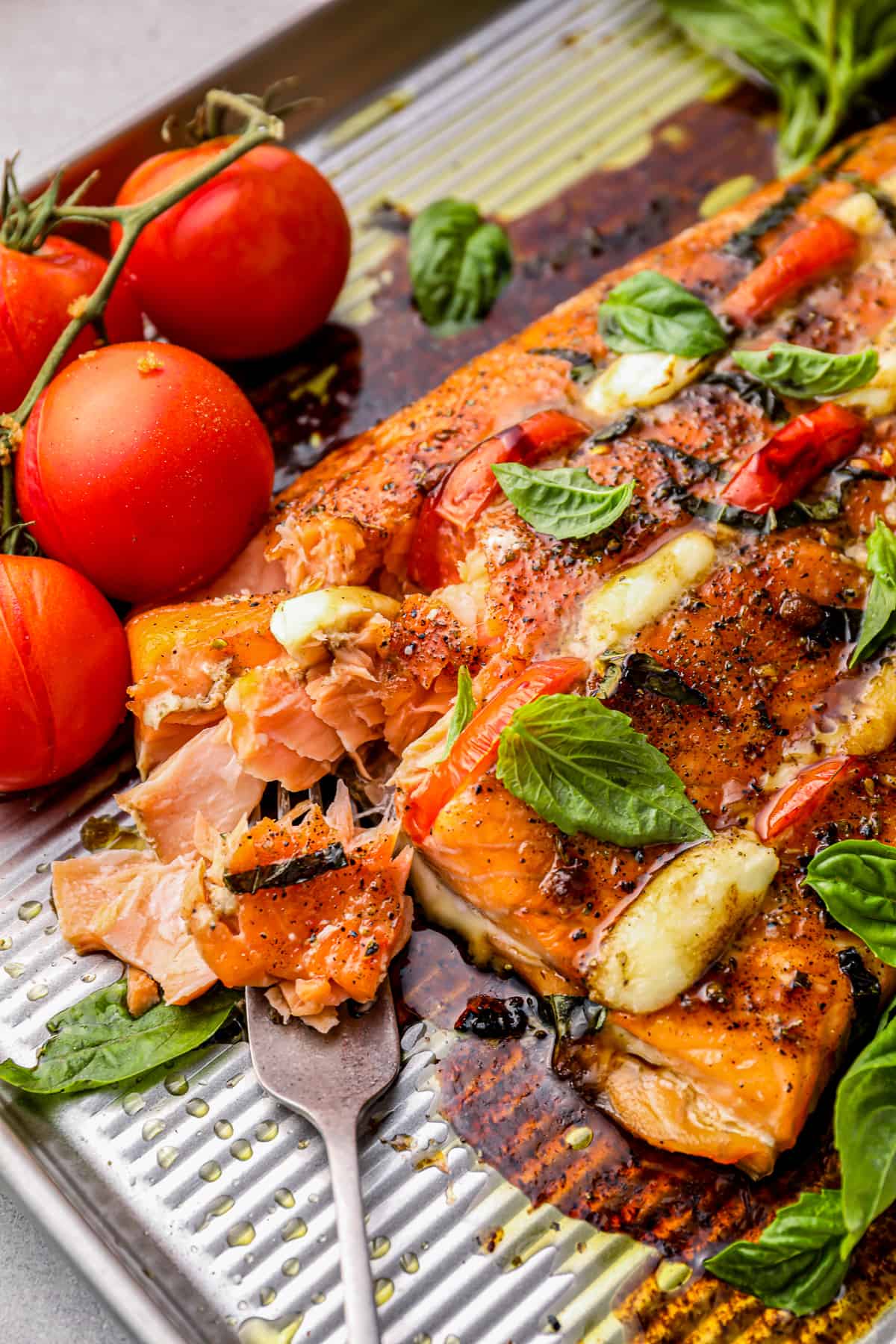 close up of caprese stuffed salmon on a baking tray.