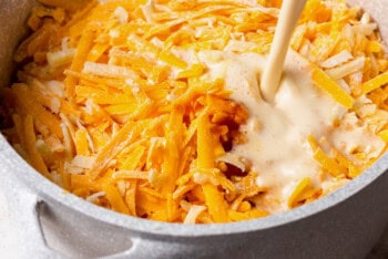 pouring cream into a pot of shredded cheese