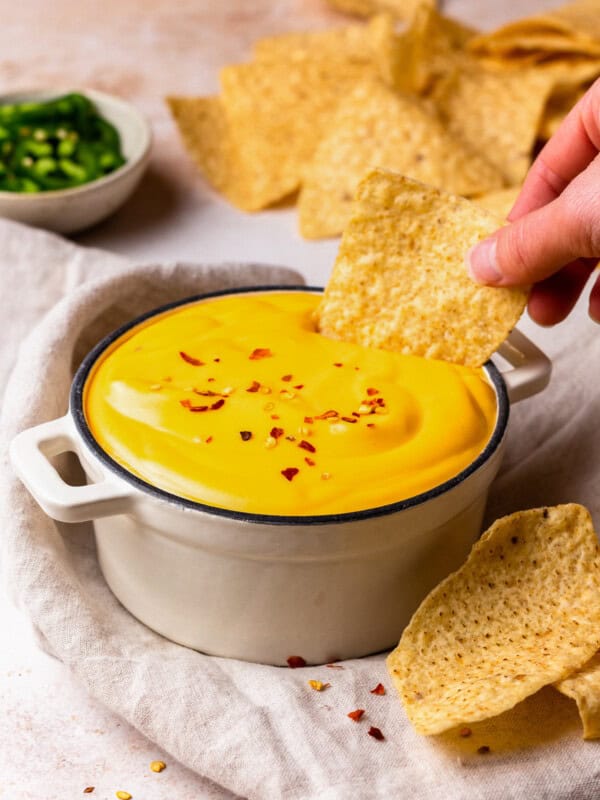 dipping a tortilla chip into a bowl of nacho cheese sauce