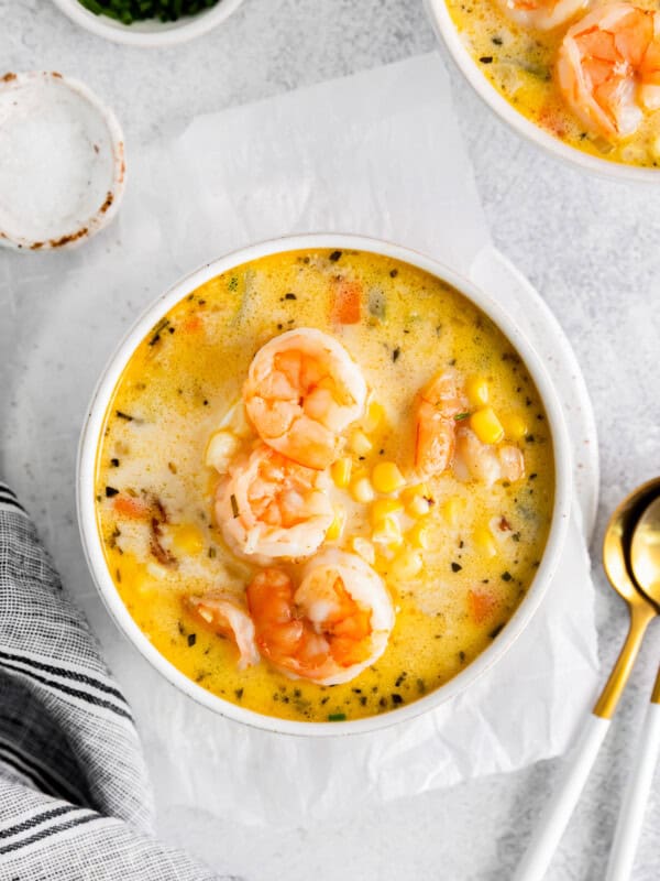 shrimp corn chowder in a white bowl with spoons.