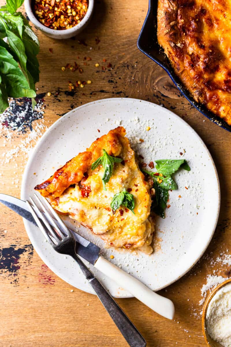 slice of deep dish skillet pizza on a white plate with fork and knife