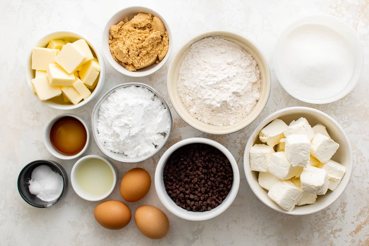 chocolate chip cheesecake bar ingredients arranged in separate bowls