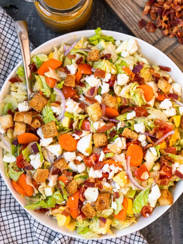 overhead view of chopped salad in a white serving bowl with a spoon.