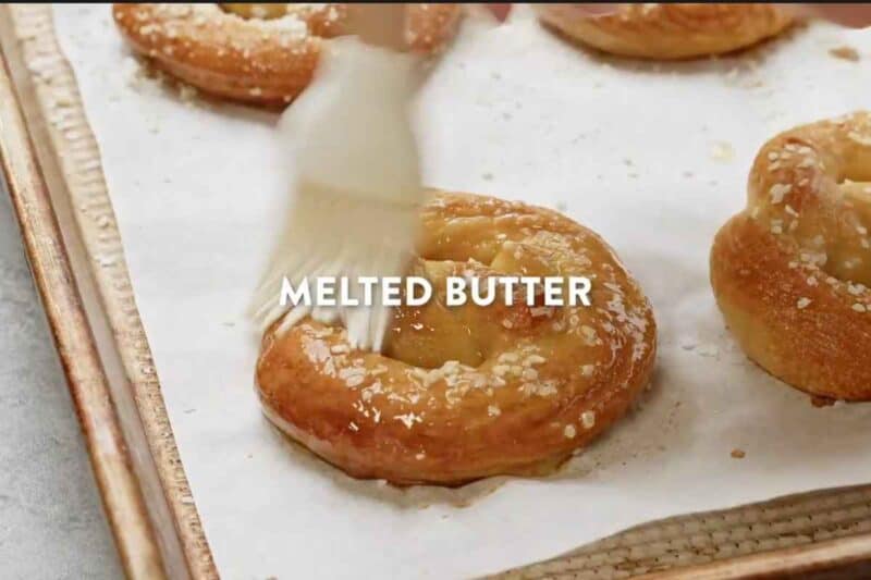 Brushing melted butter on a baked pretzel