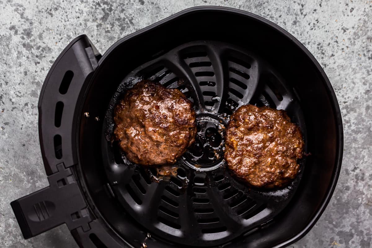 two burgers cooking in an air fryer