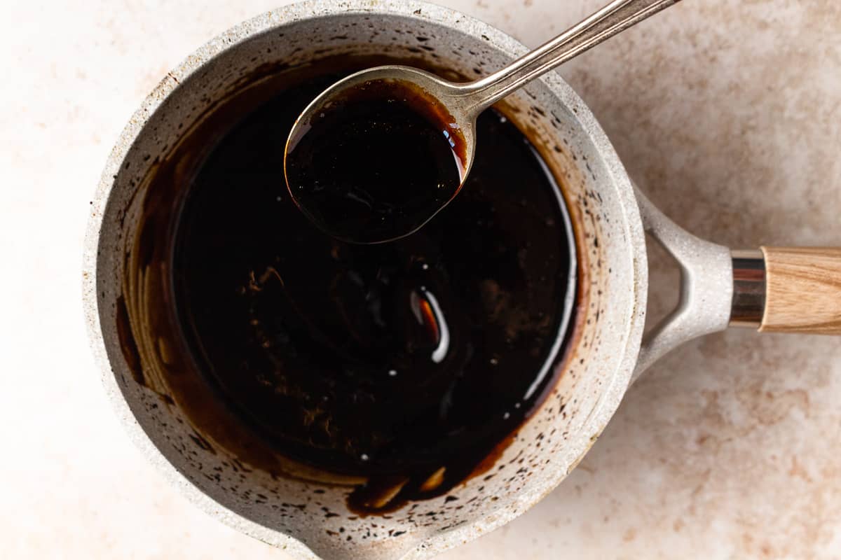 Spoon stirring balsamic glaze as it reduces in a saucepan.