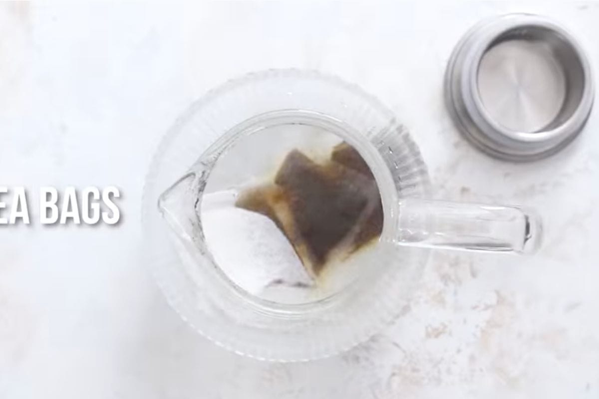 adding tea bags in glass pitcher filled with boiling water.