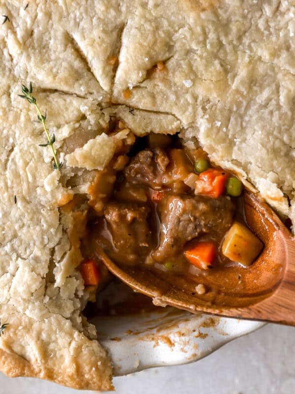 closeup overhead view of a cut beef pot pie with the filling exposed on a wooden spoon.