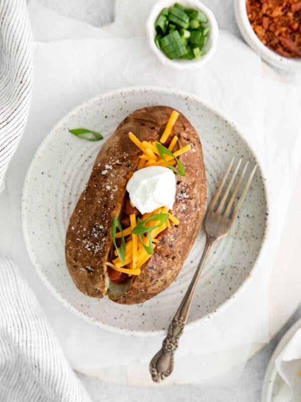 overhead view of a loaded air fryer baked potato on a white plate with a fork.