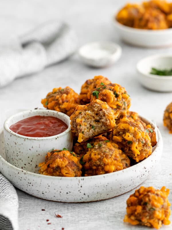 air fryer sausage balls on a white plate with sweet chili ketchup.