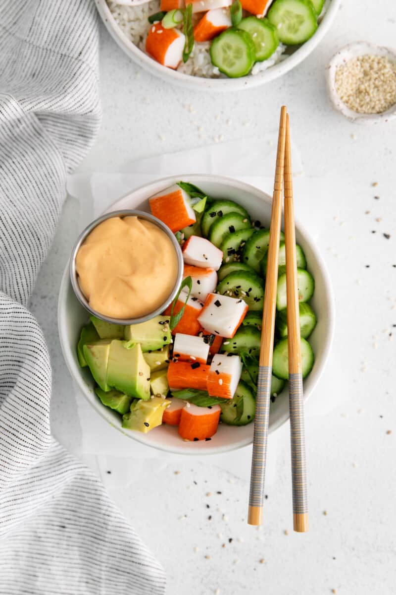 overhead view of a sushi bowl filled with cucumbers, avocado, imitation crab, and more