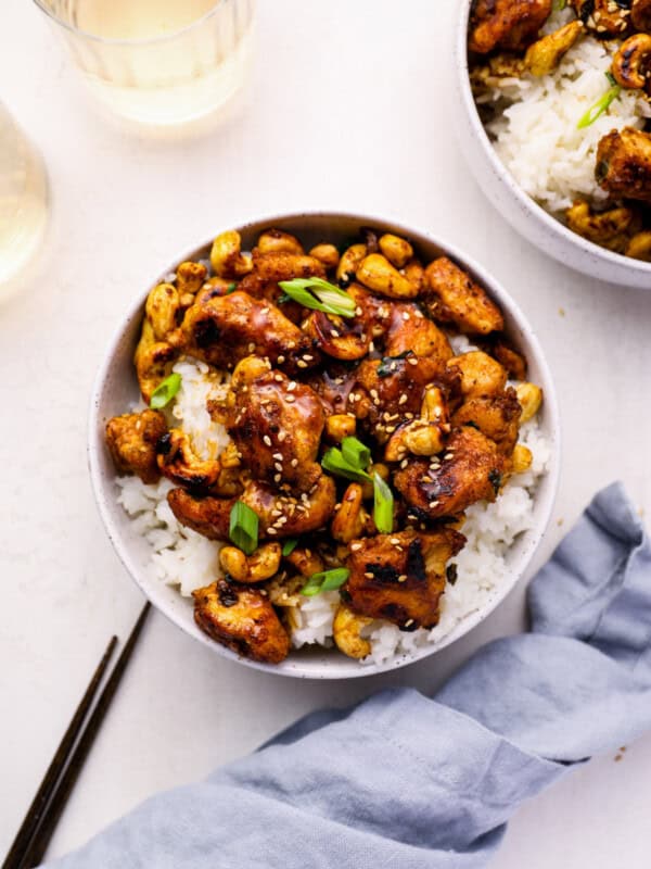 overhead view of cashew chicken in a white bowl with chopsticks.