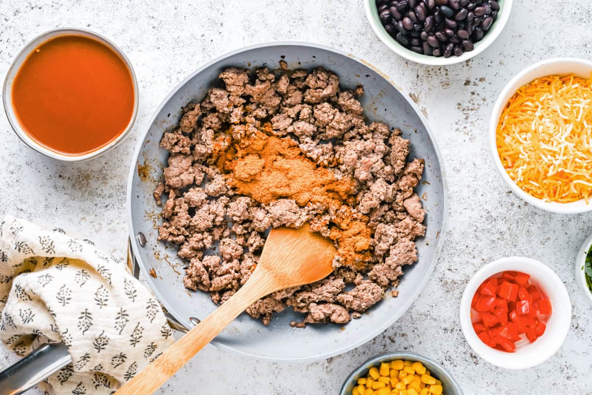 ground beef with taco seasoning in a frying pan with a wooden spoon.