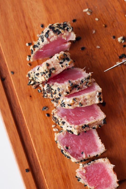 close up on sesame seared ahi tuna, sliced thinly on a cutting board