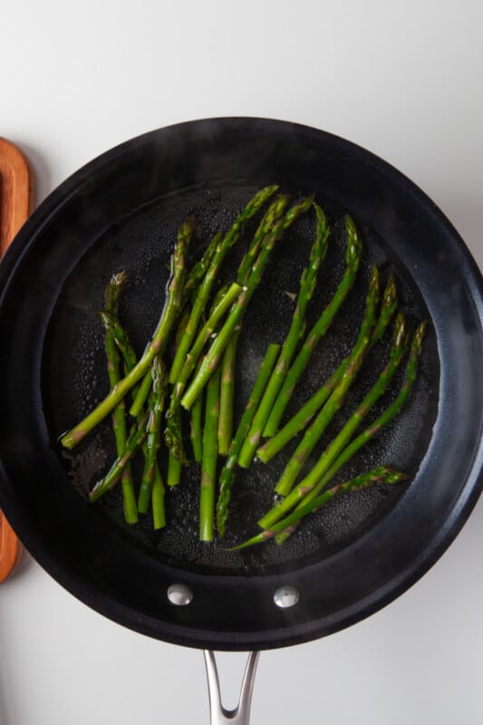 sautéing stalks of asparagus in a skillet