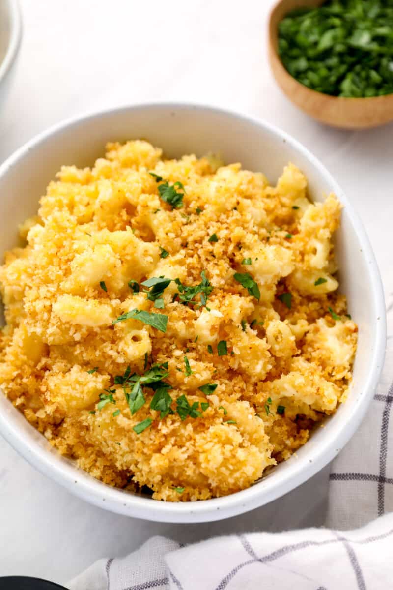 a serving of mac and cheese casserole in a white bowl with parsley.