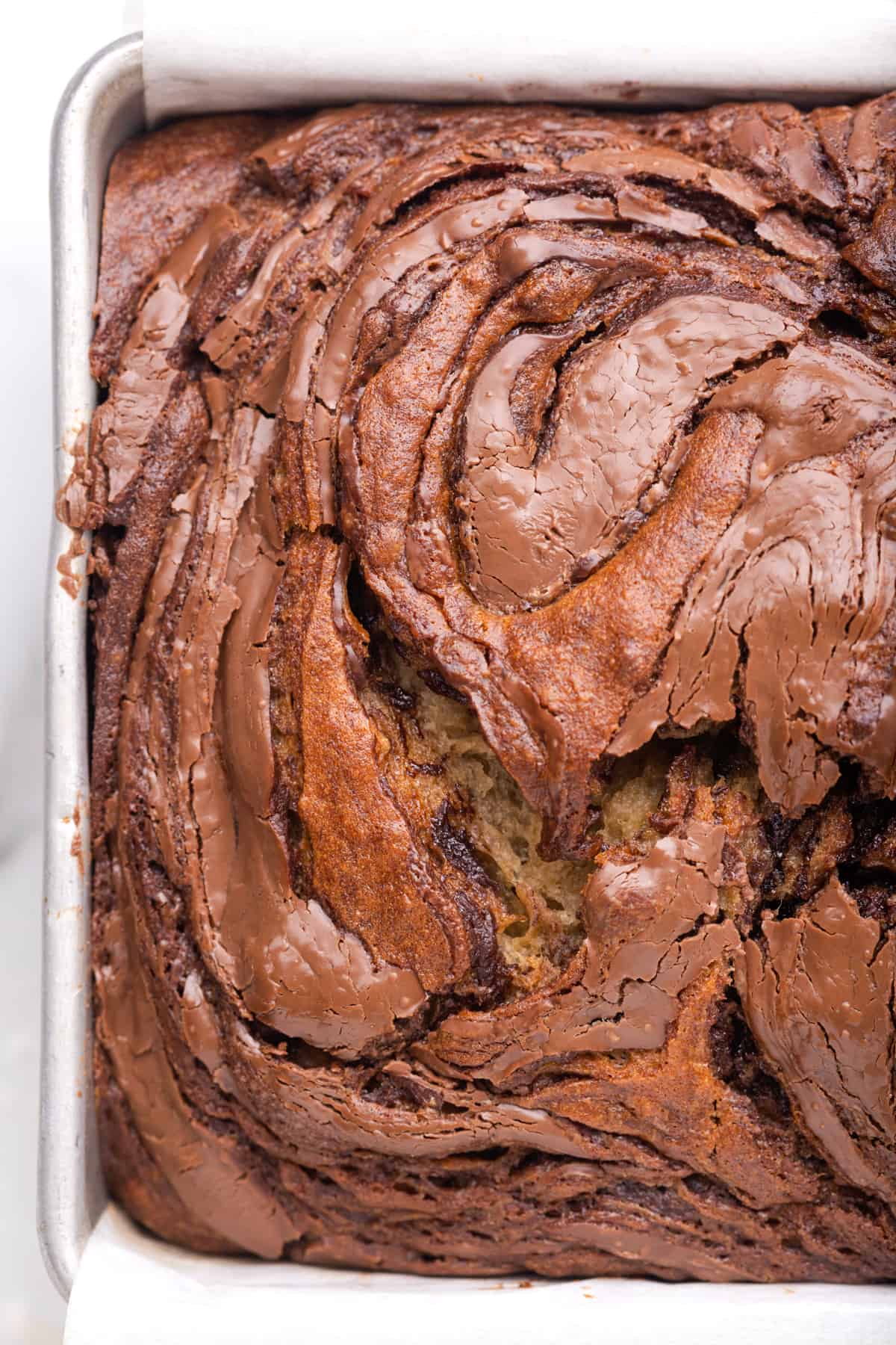 close up of banana bread with Nutella swirl in a loaf pan.