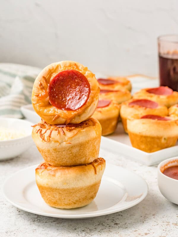 a turned pizza cupcake stacked on 2 upright pizza cupcakes on a white plate.