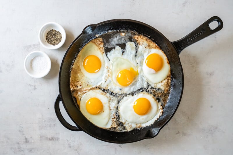 overhead view of fried eggs in a cast iron skillet.