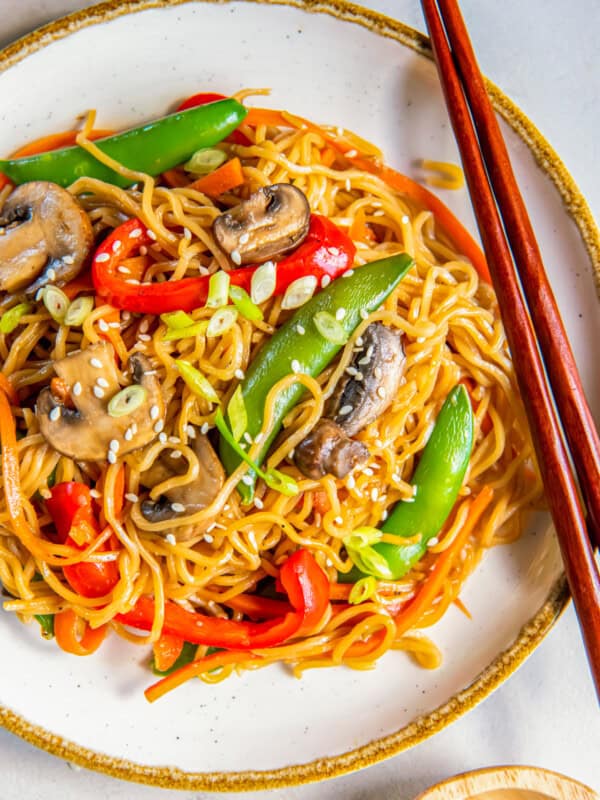 overhead view of vegetable lo mein on a white plate with chopsticks.