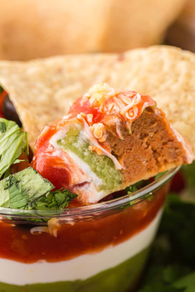 close up of a chip scooping 7 layer dip from a dip cup.