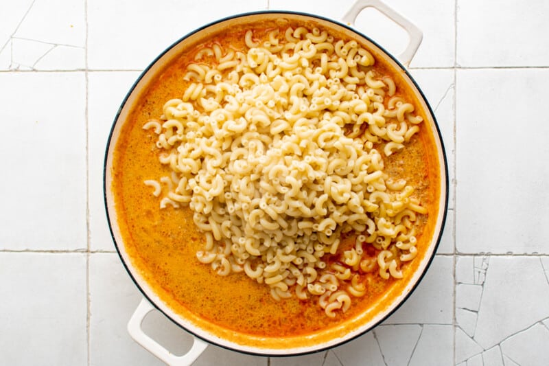 overhead view of pasta added to hamburger helper in a white pan.