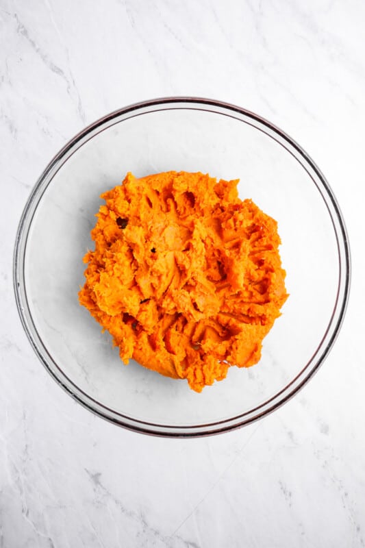 overhead view of mashed sweet potato in a glass bowl.