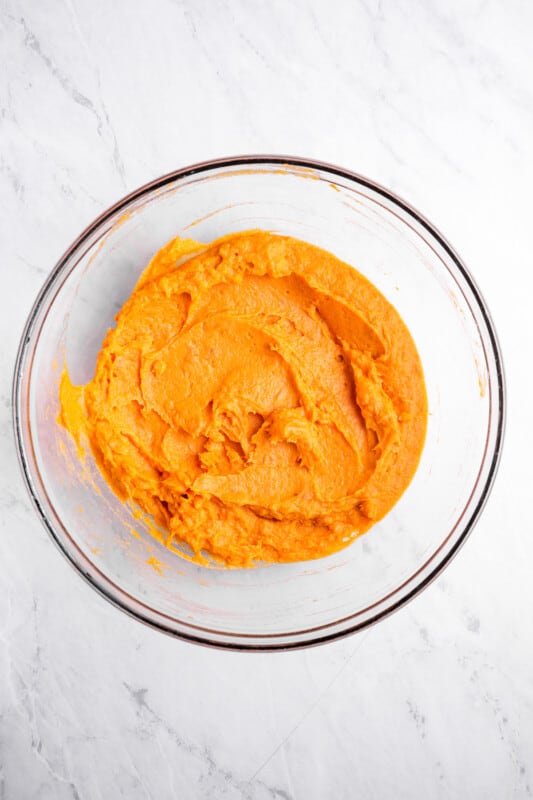 overhead view of mashed sweet potato and egg in a glass bowl.