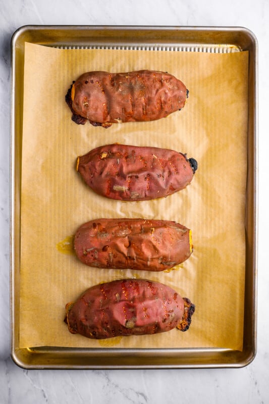 overhead view of 4 roasted sweet potato halves on a baking sheet.