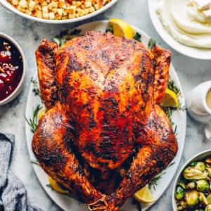 whole roast thanksgiving turkey at the center of a table, surrounded by side dishes