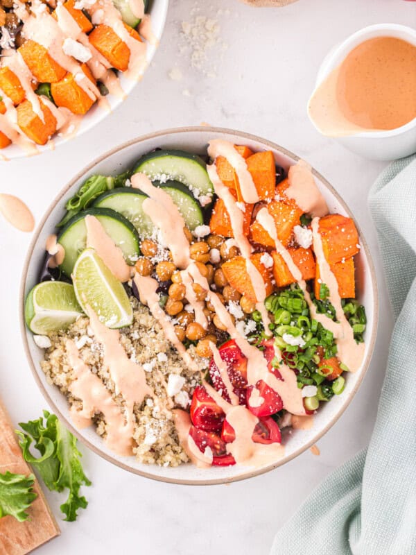 overhead view of a buddha bowl drizzled with sriracha mayo dressing in a white bowl.