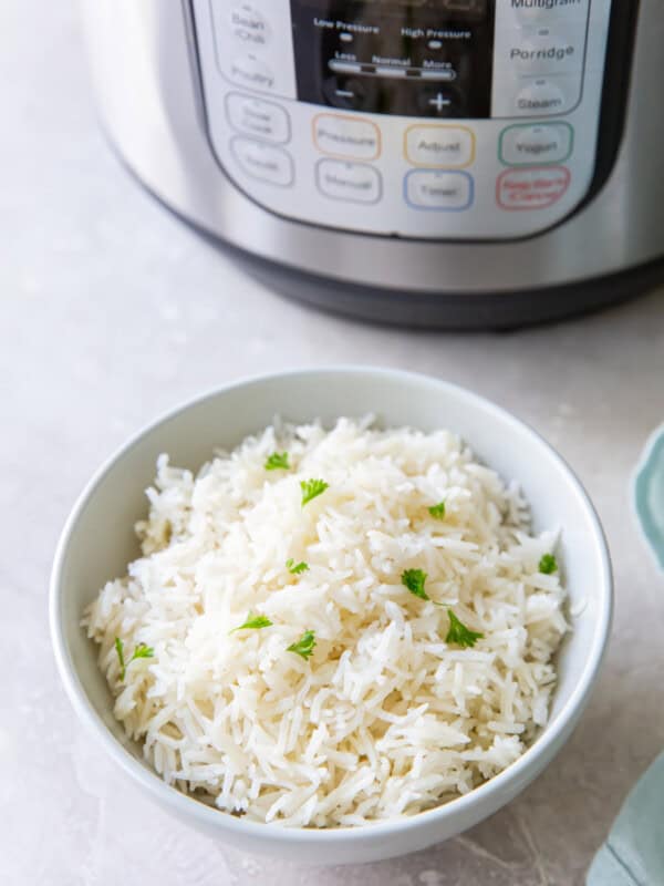 instant pot basmati rice in a white bowl next to an instant pot.